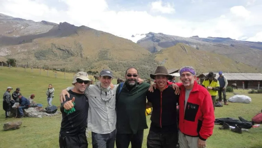 Base camp at the foot of the Sierra Nevada del Cocuy, with a mountaineering expedition gathered in front of the snow-covered mountains