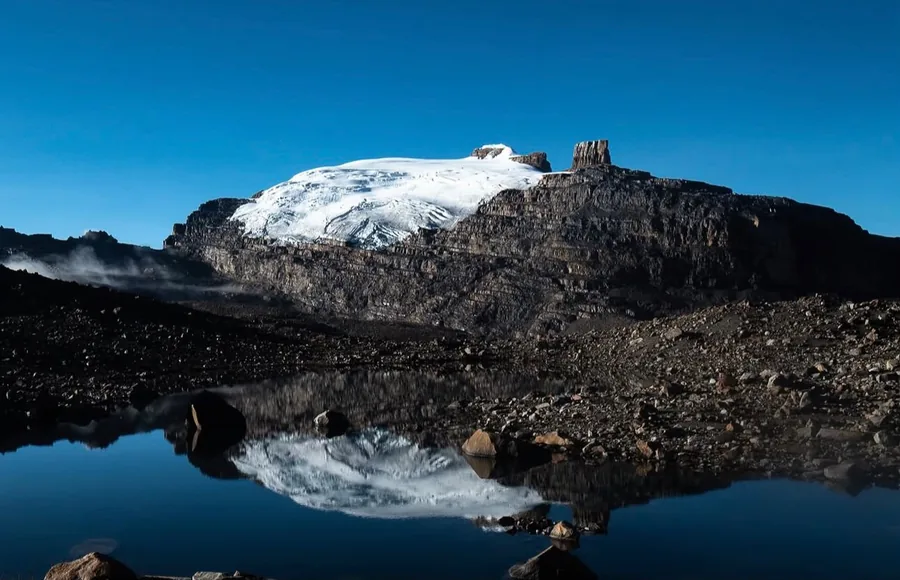 The snow-covered Pan de Azúcar and the rock tower of the Púlpito del Diablo reflected in a lake in El Cocuy National Natural Park